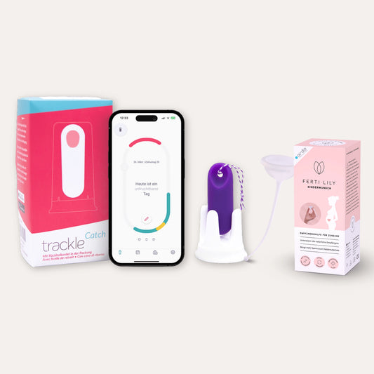 Produkt-Bundle für die Empfängnis: Das Bild stellt die trackleCatch Verpackung, ein Smartphone mit der trackle App (Anzeige eines unfruchtbaren Tages), den lila trackleCatch in seiner Halterung sowie die FERTI-LILY Empfängnishilfe mit der dazugehörigen rosa Verpackung dar. Ein komplettes System zur Bestimmung der fruchtbaren Tage und zur Unterstützung der natürlichen Befruchtung.