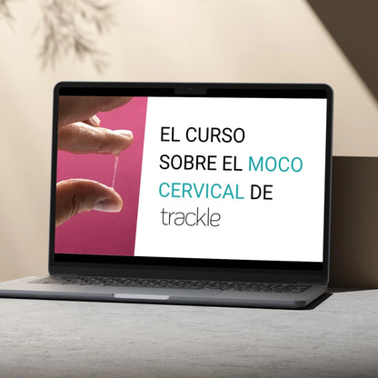 Un ordenador portátil sobre una mesa gris, con un fondo claro, muestra la pantalla de inicio del «curso sobre el moco cervical de trackle». El diseño incluye un primer plano del análisis del moco y un retrato de la experta.