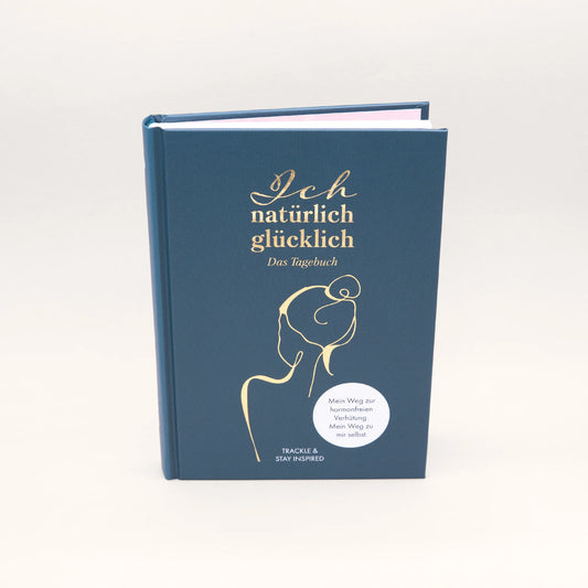 Außenansicht des Tagebuchs 'Ich natürlich glücklich'. Ein dunkelblaues Hardcover-Buch mit hochwertiger Goldprägung. Das Cover zeigt eine minimalistische Frauen-Silhouette in Linienzeichnung und den Untertitel 'Mein Weg zur hormonfreien Verhütung. Mein Weg zu mir selbst.'
