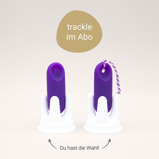 Infografik zur Auswahl der trackle Abo-Modelle. Oben ein goldener Kreis mit dem Text 'trackle im Abo'. Darunter stehen zwei lila Zyklussensoren in weißen Halterungen nebeneinander: links der trackleRegular ohne Kordel, rechts der trackleCatch mit einer lila-weiß gestreiften Rückholkordel. Zwei Pfeile zeigen auf die Sensoren mit der Unterschrift: 'Du hast die Wahl!'.