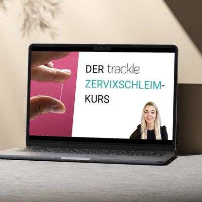 Ein Laptop auf einem grauen Tisch vor hellem Hintergrund zeigt den Startbildschirm des 'trackle Zervixschleim-Kurses'. Das Design enthält eine Nahaufnahme der Schleimprüfung und ein Porträt der Expertin.